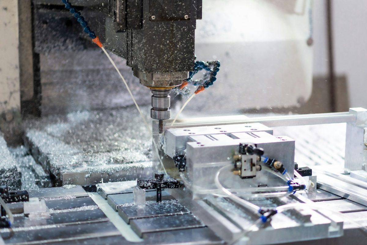 CNC machining center cutting a metal part under coolant spray